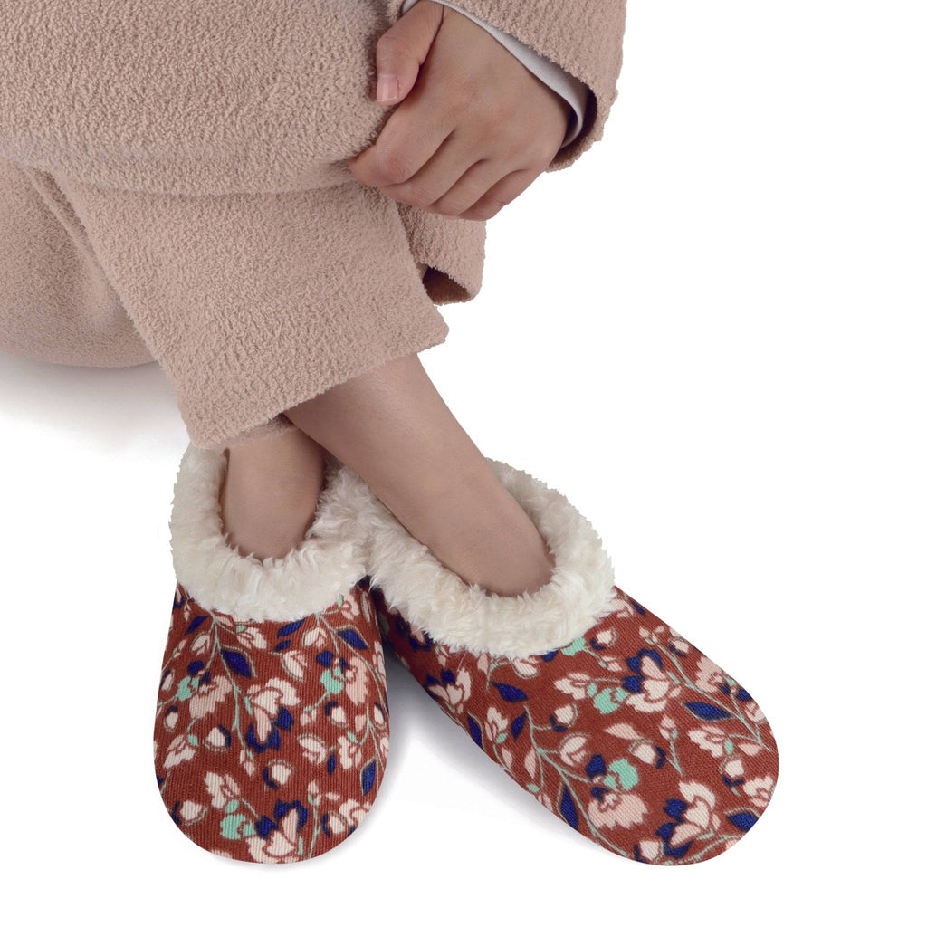 Floral patterned slippers with white fur lining worn by a person on a white background