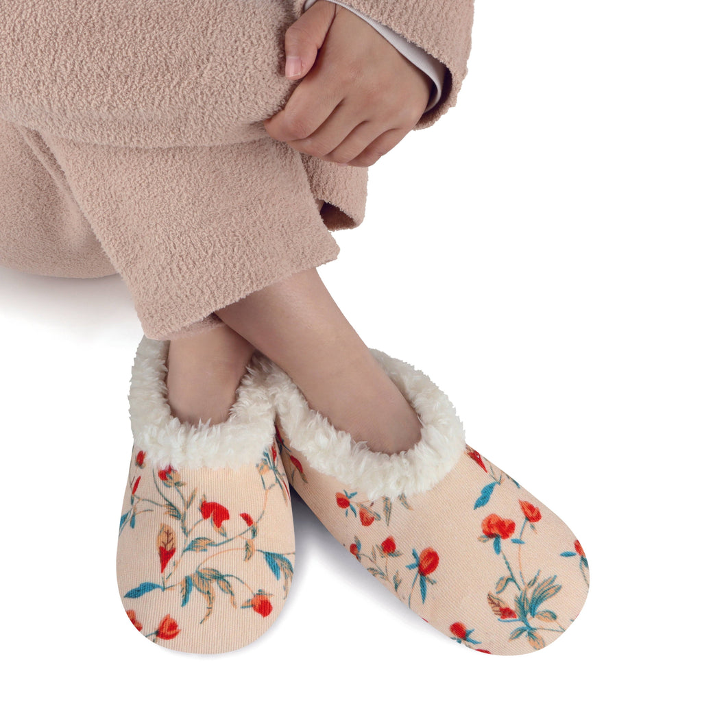 Floral patterned slippers worn with a beige fleece-lined interior on a white background