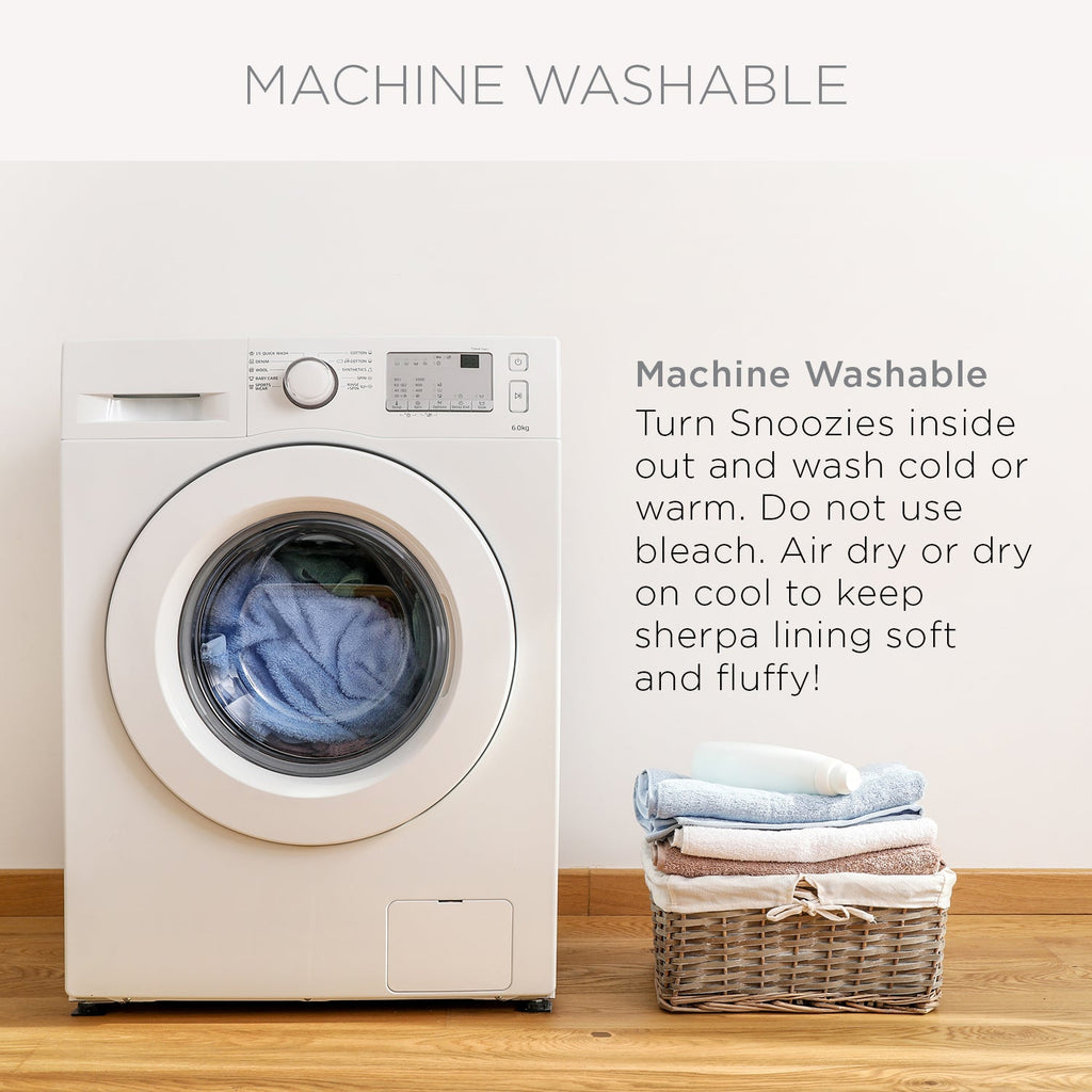 An image titled "MACHINE WASHABLE" showing a white front-loading washing machine next to a wicker basket of folded towels. The text provides washing instructions, stating: "Machine Washable. Turn Snoozies inside out and wash cold or warm. Do not use bleach. Air dry or dry on cool to keep sherpa lining soft and fluffy!"